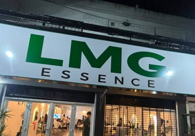Fachada del salón con el cartel LMG iluminado de noche.