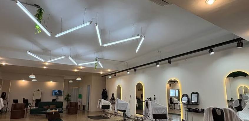 Vista amplia del salón LMG: techo con tubos de luz en zigzag y espejos arqueados iluminados.